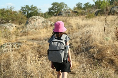 Little girl travelling at field, back view