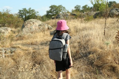 Photo of Little girl travelling at field, back view