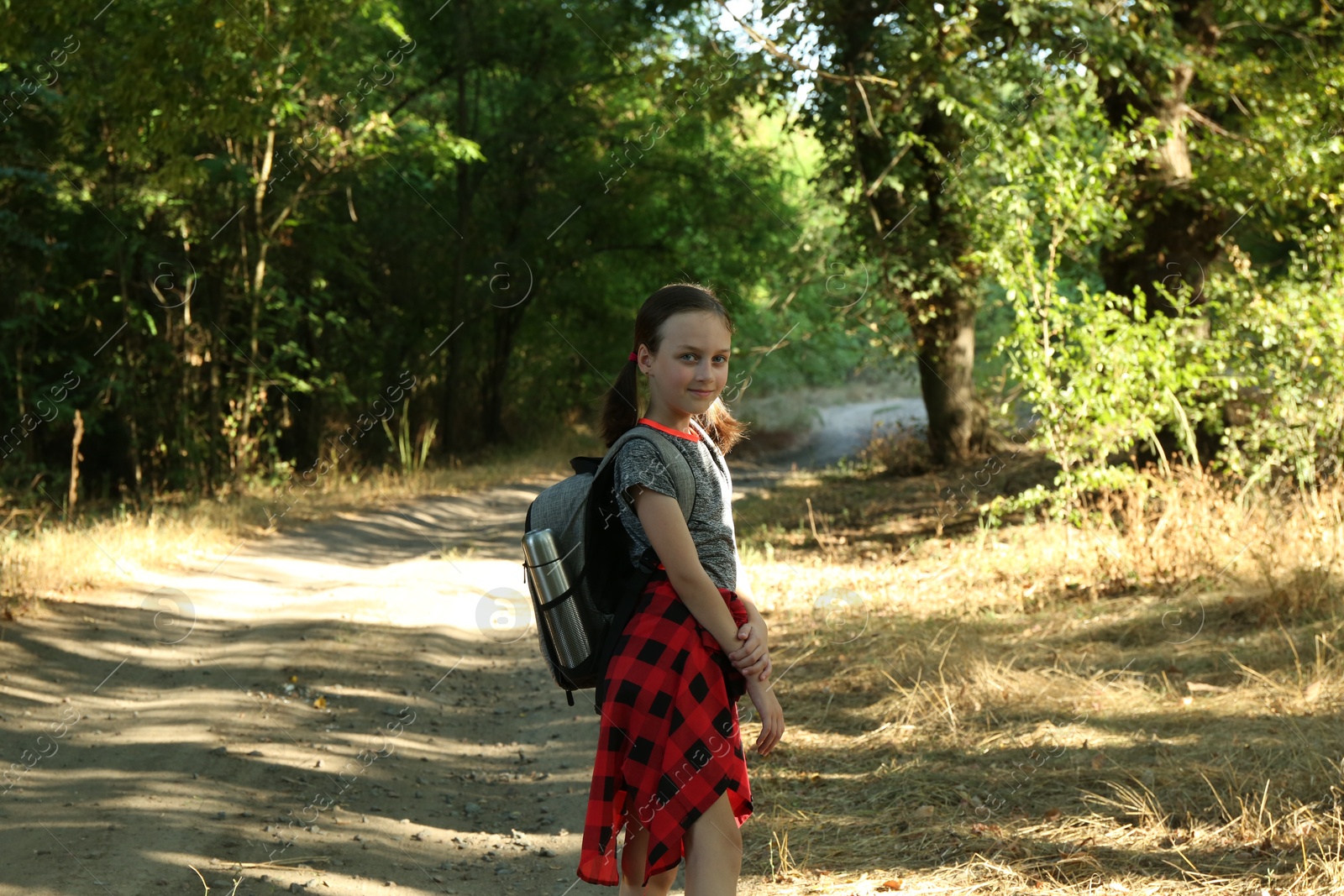 Photo of Little girl with backpack travelling in beautiful forest