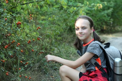 Portrait of little girl near shrub with berries outdoors