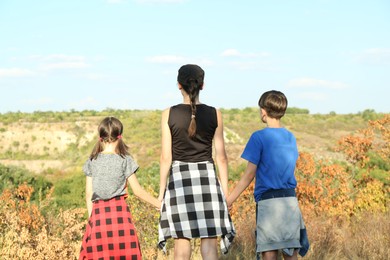 Photo of Family enjoying picturesque landscape on sunny day, back view