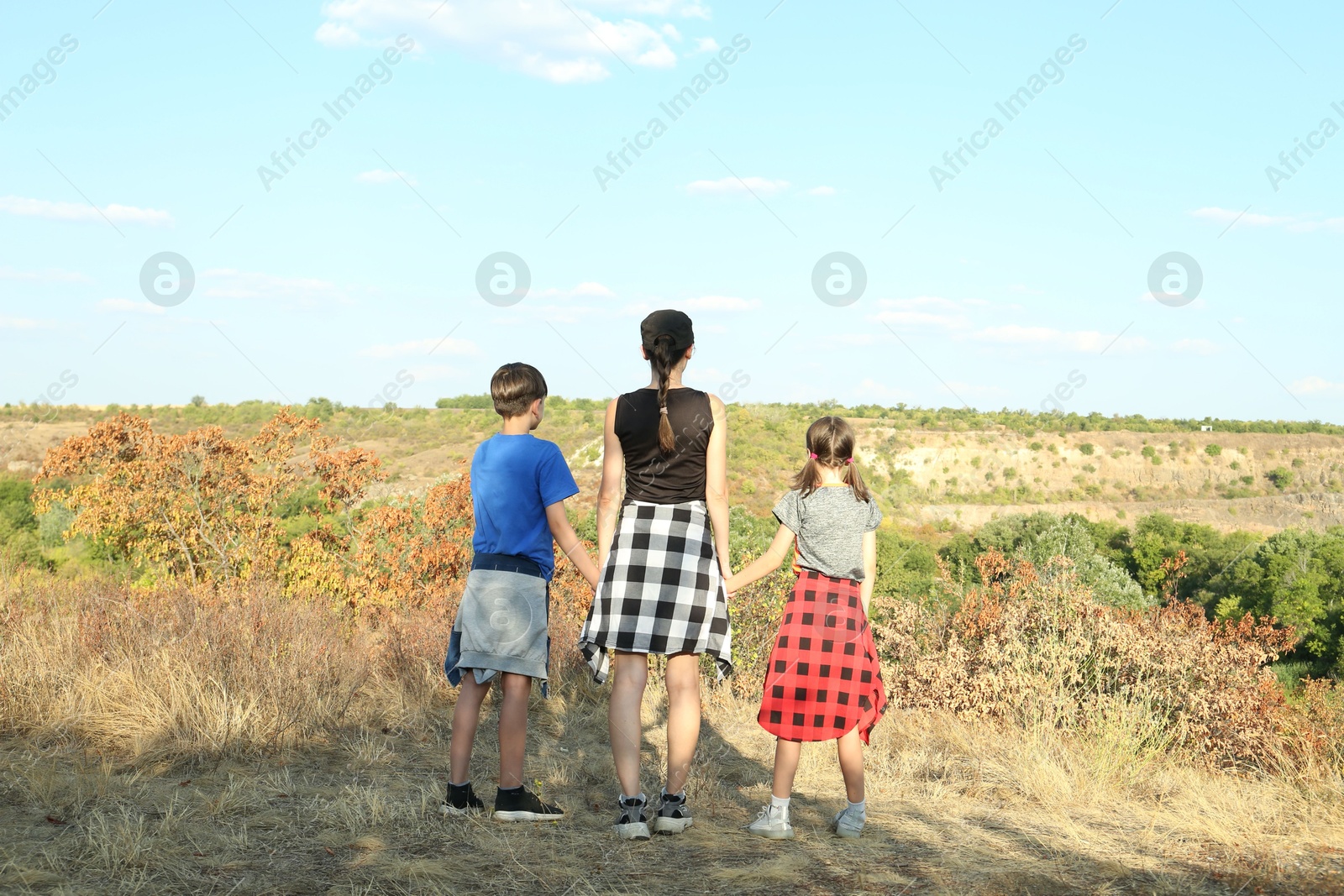 Photo of Family enjoying picturesque landscape on sunny day, back view