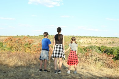 Photo of Family enjoying picturesque landscape on sunny day, back view