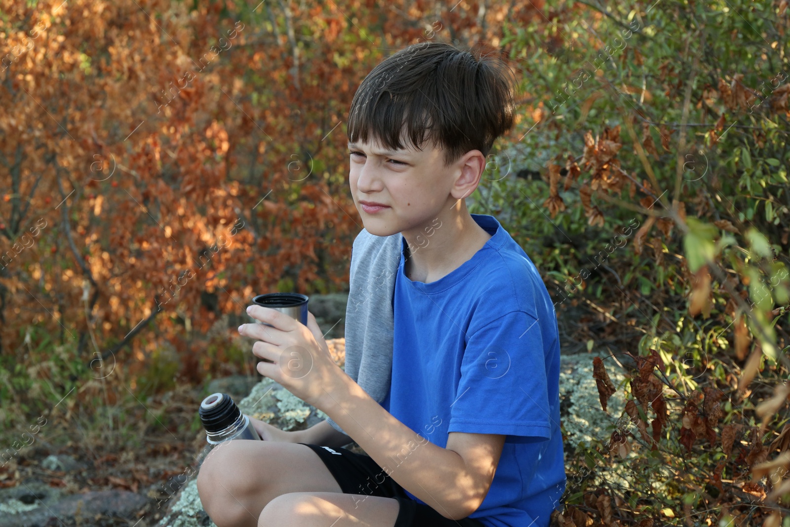 Photo of Little boy drinking tea among trees outdoors