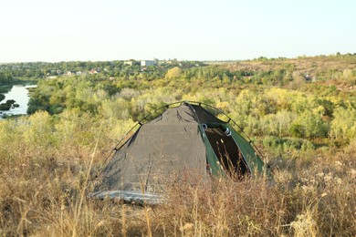 Photo of One camping tent among plants outdoors on sunny day