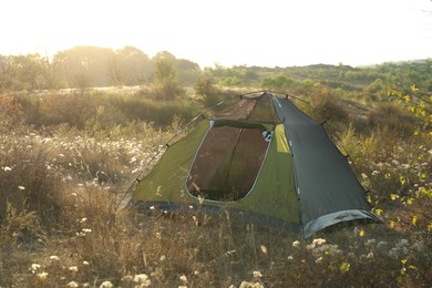 Photo of One camping tent among plants outdoors on sunny day