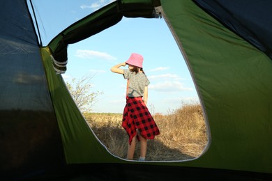 Photo of Little girl, blue sky and grass, view from camping tent