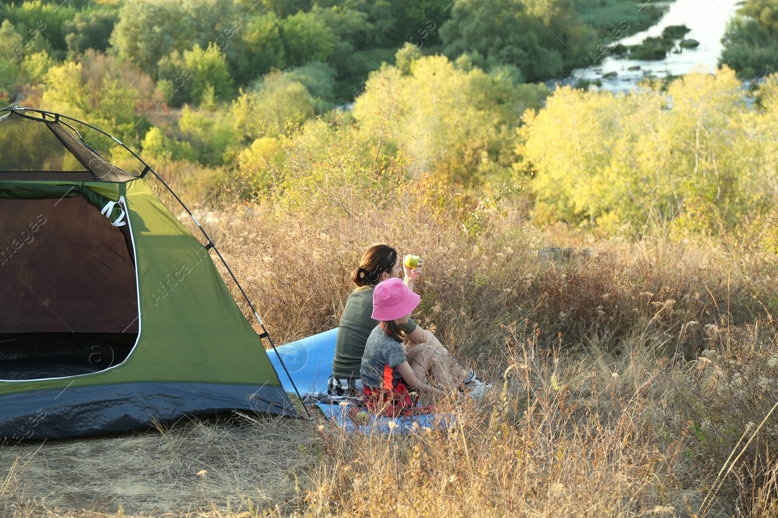 Photo of Mother and daughter enjoying picturesque view near camping tent