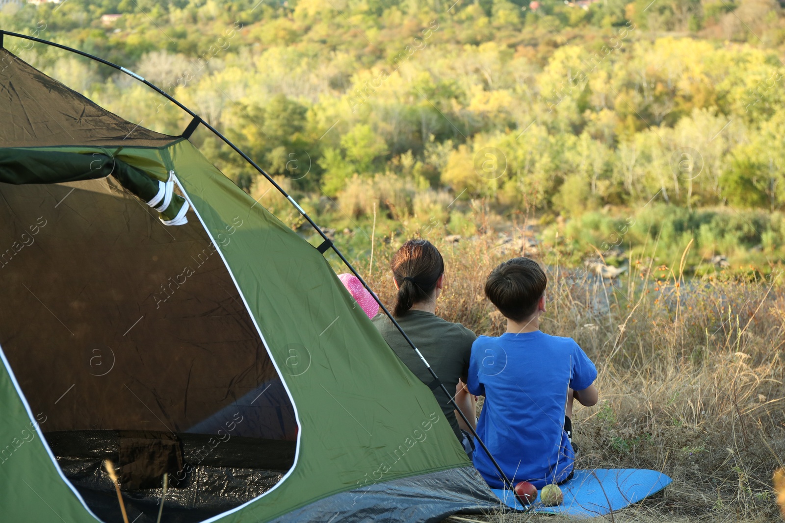 Photo of Family enjoying picturesque view near camping tent, back view