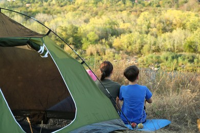 Photo of Family enjoying picturesque view near camping tent, back view