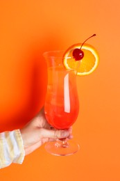 Photo of Woman with glass of refreshing cocktail on orange background, closeup