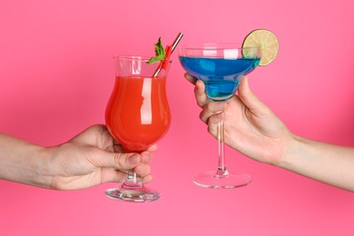 Photo of Friends with glasses of refreshing cocktails on pink background, closeup