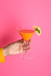 Photo of Woman with glass of refreshing cocktail on pink background, closeup