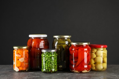 Photo of Different pickled products in jars on grey textured table