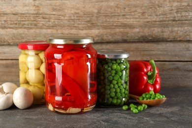 Photo of Different pickled products in jars on grey textured table