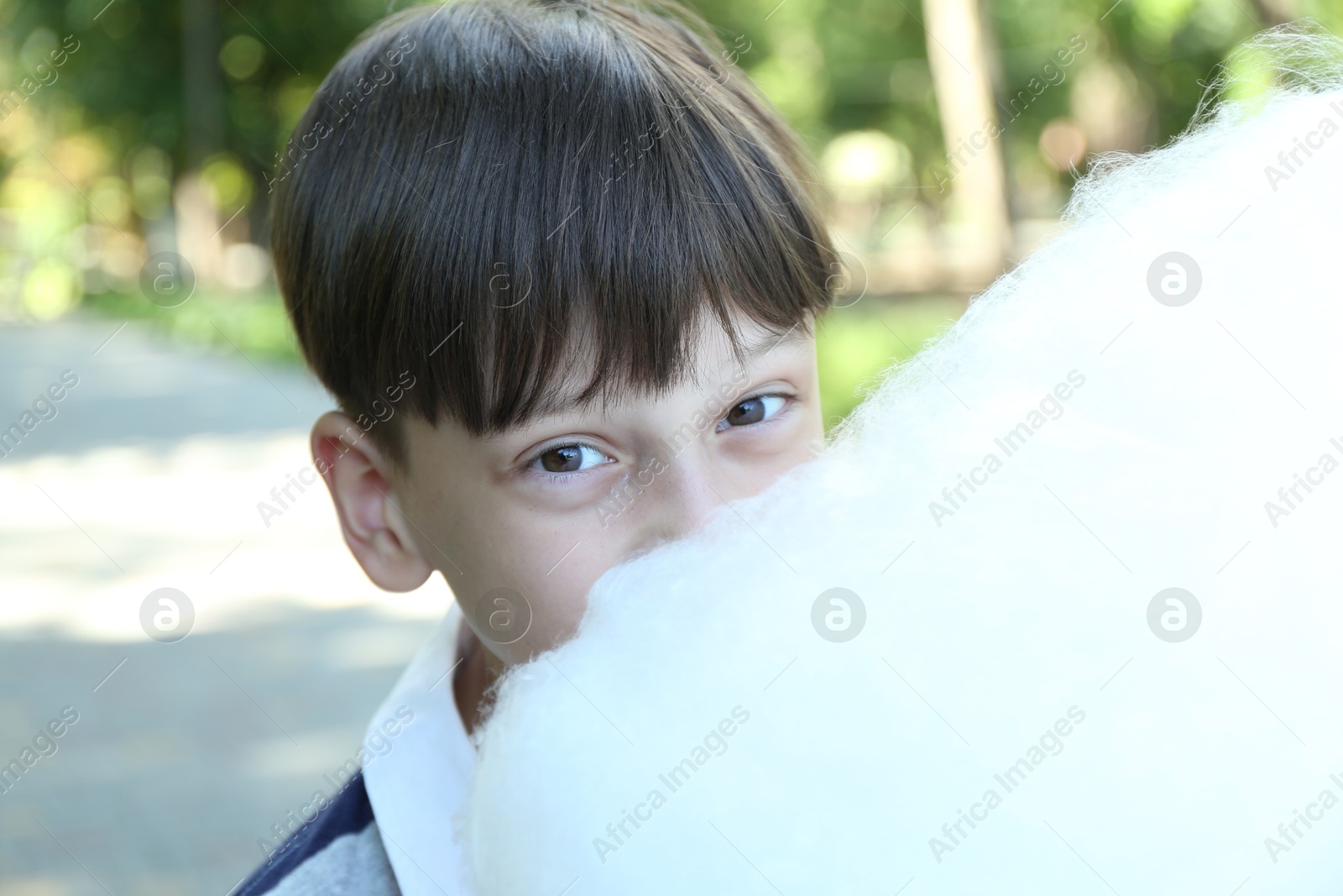 Photo of Portrait of little boy eating sweet cotton candy in park