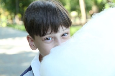 Photo of Portrait of little boy eating sweet cotton candy in park