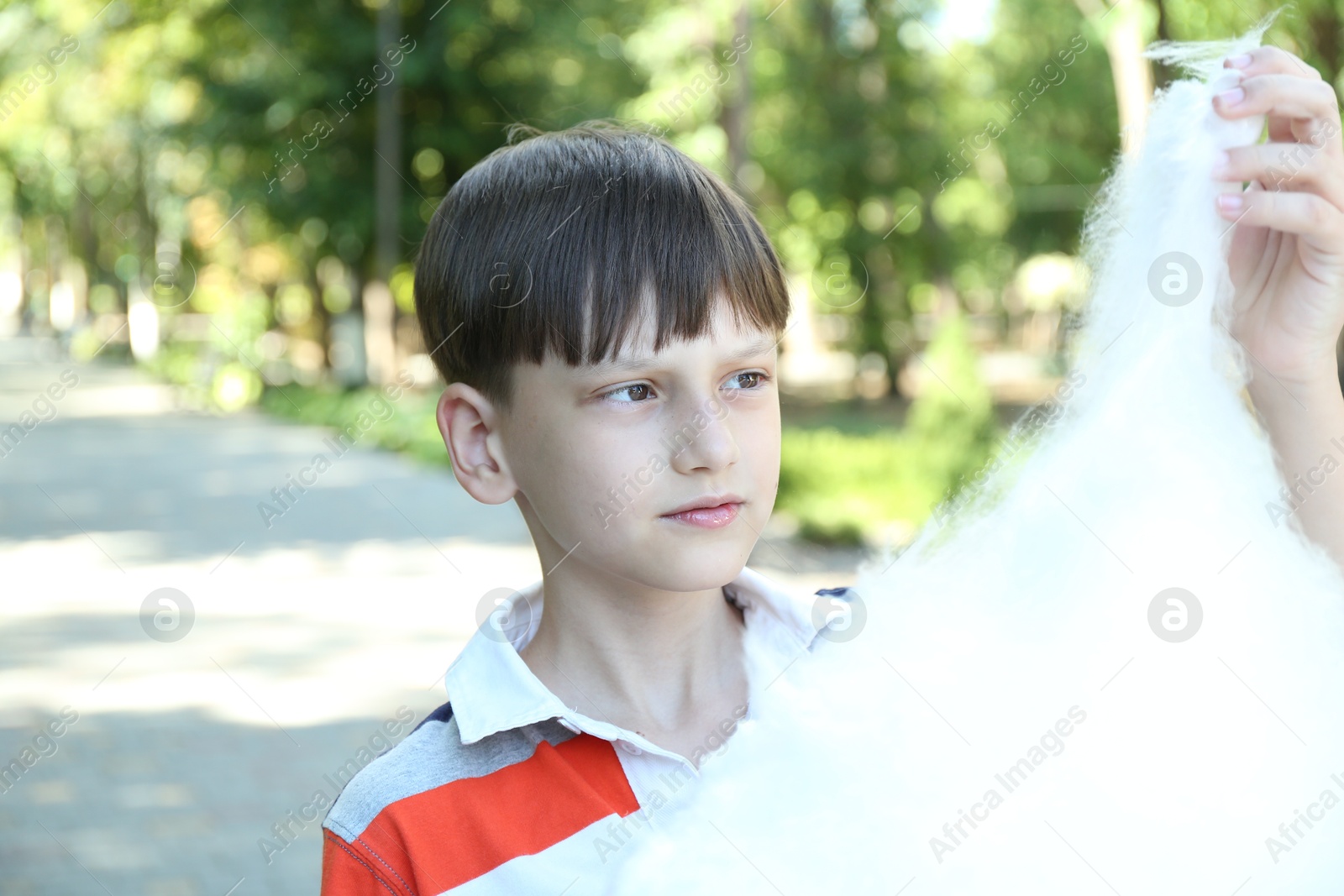 Photo of Portrait of little boy eating sweet cotton candy in park