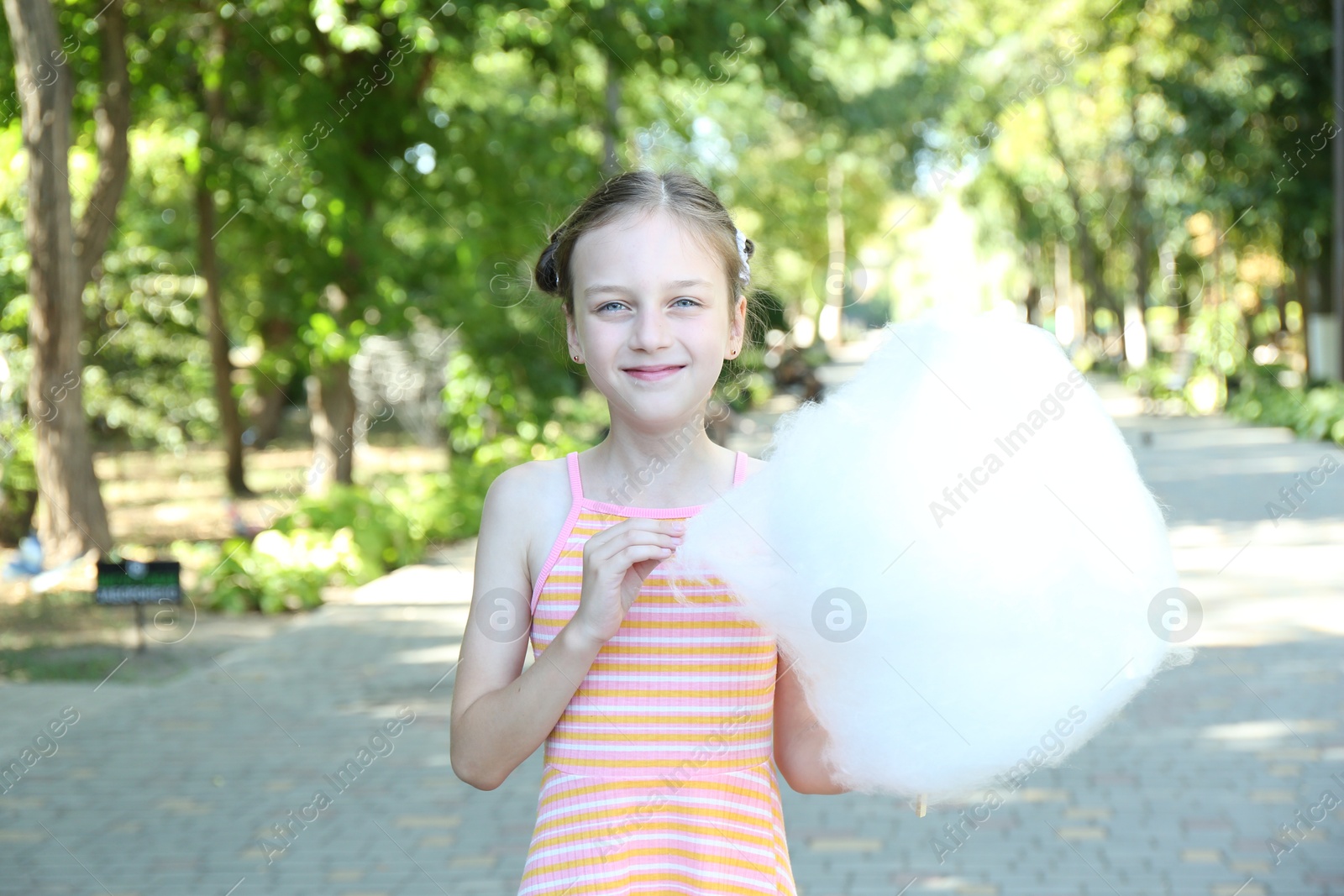 Photo of Portrait of little girl with sweet cotton candy in park