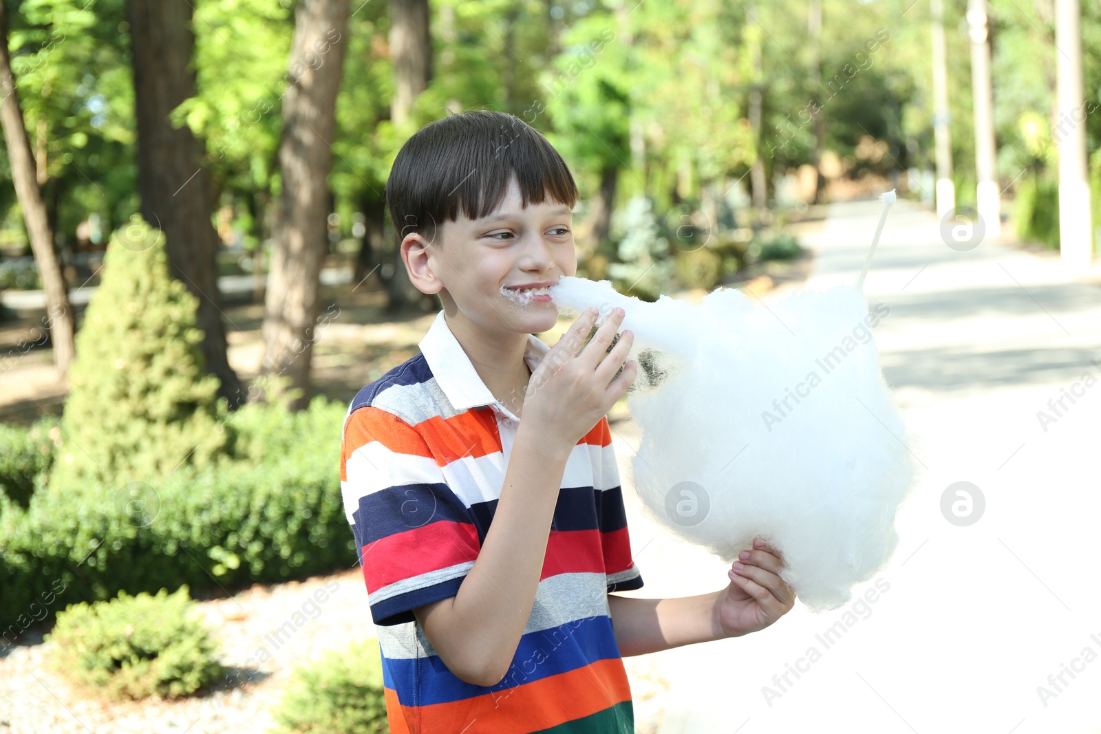 Photo of Portrait of little boy eating sweet cotton candy in park