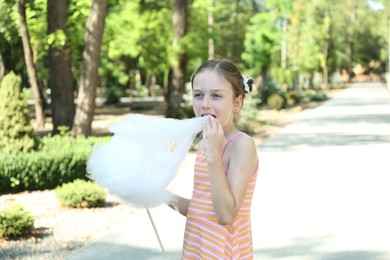 Portrait of little girl eating sweet cotton candy in park