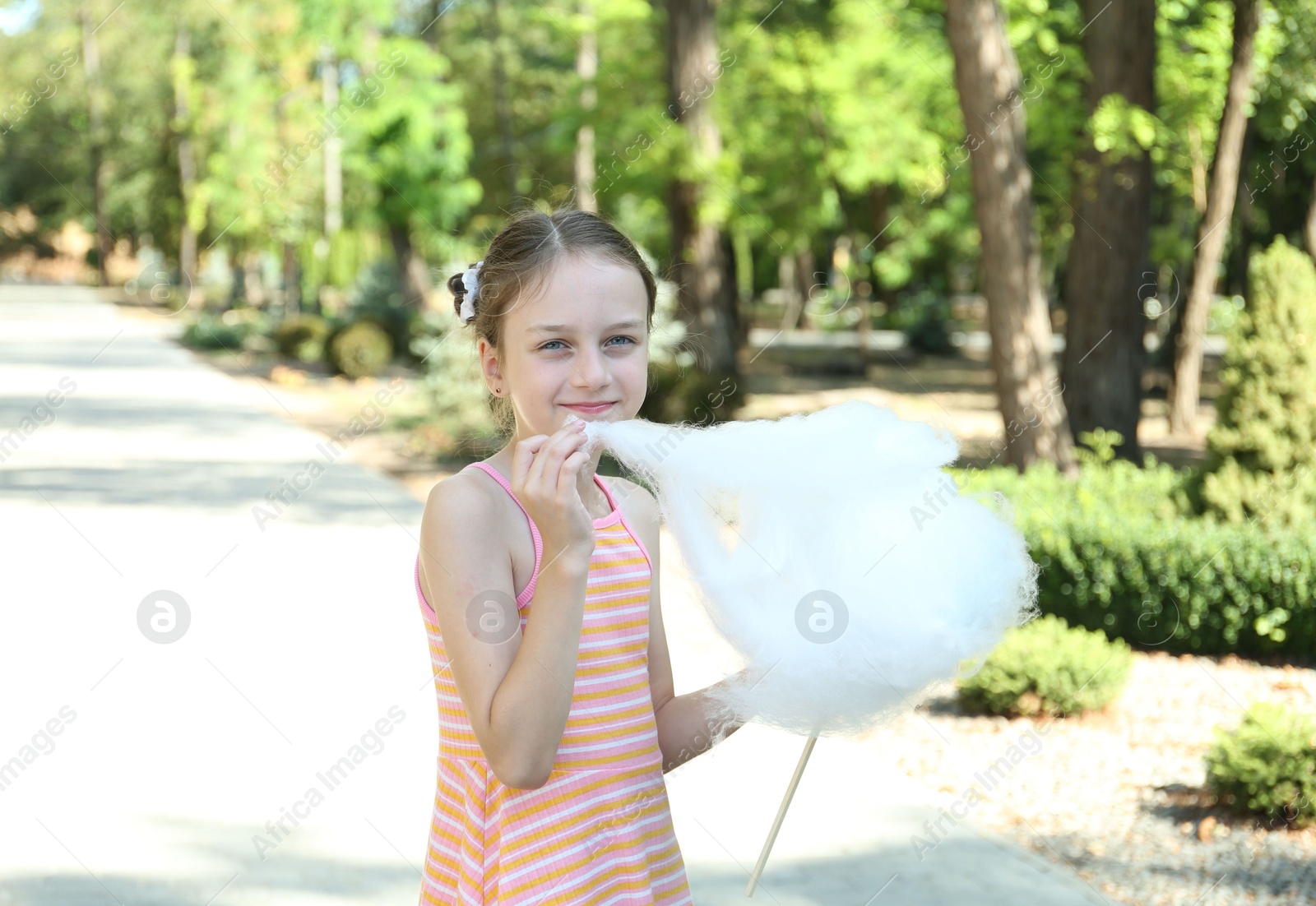 Photo of Portrait of little girl with sweet cotton candy in park