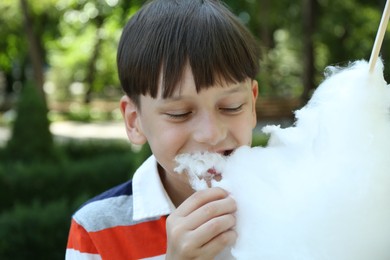 Photo of Portrait of little boy eating sweet cotton candy in park