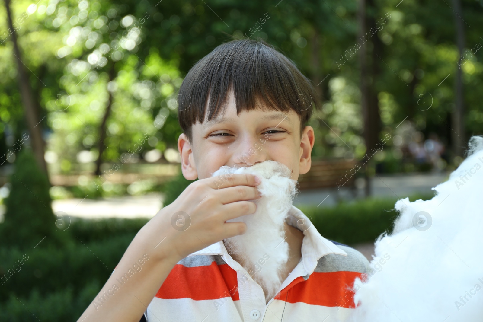 Photo of Portrait of little boy eating sweet cotton candy in park