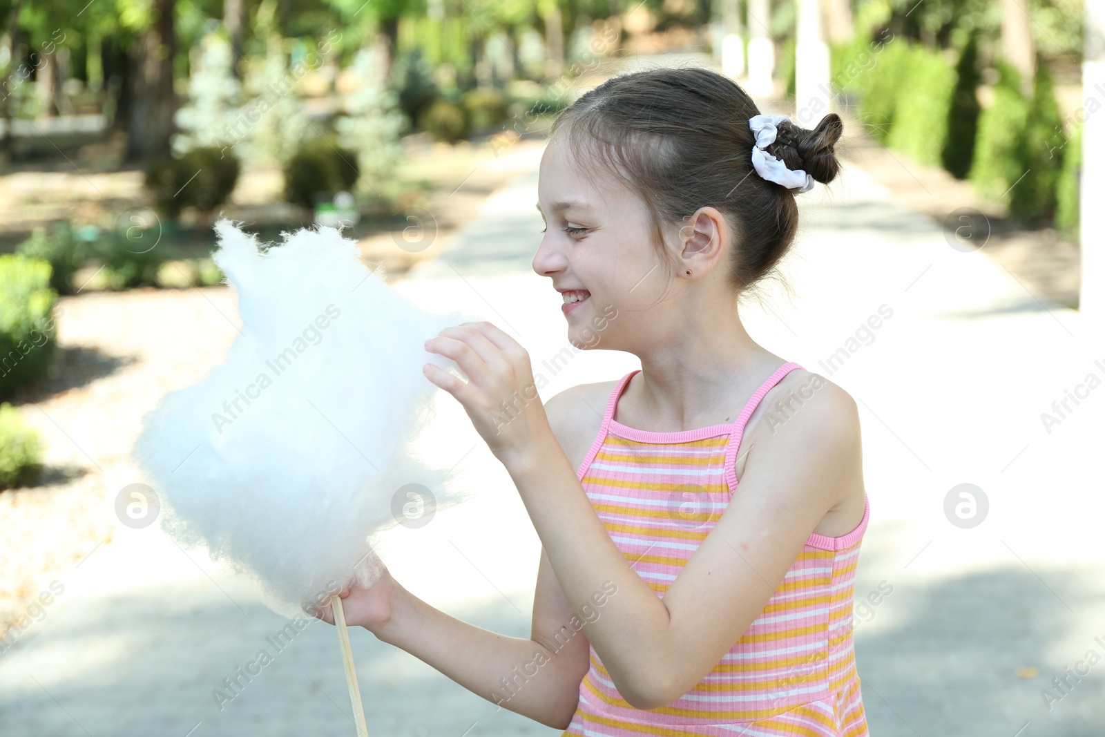 Photo of Portrait of little girl eating sweet cotton candy in park