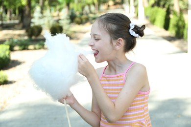 Photo of Portrait of little girl eating sweet cotton candy in park