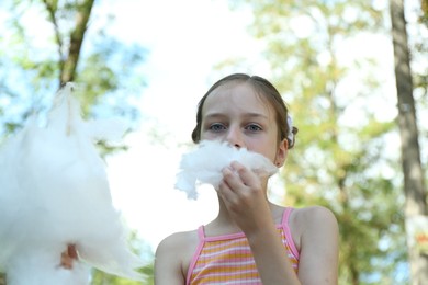 Photo of Portrait of little girl eating sweet cotton candy in park