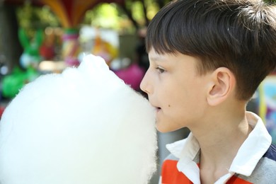 Photo of Portrait of little boy eating sweet cotton candy in park