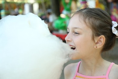 Photo of Portrait of little girl eating sweet cotton candy in park