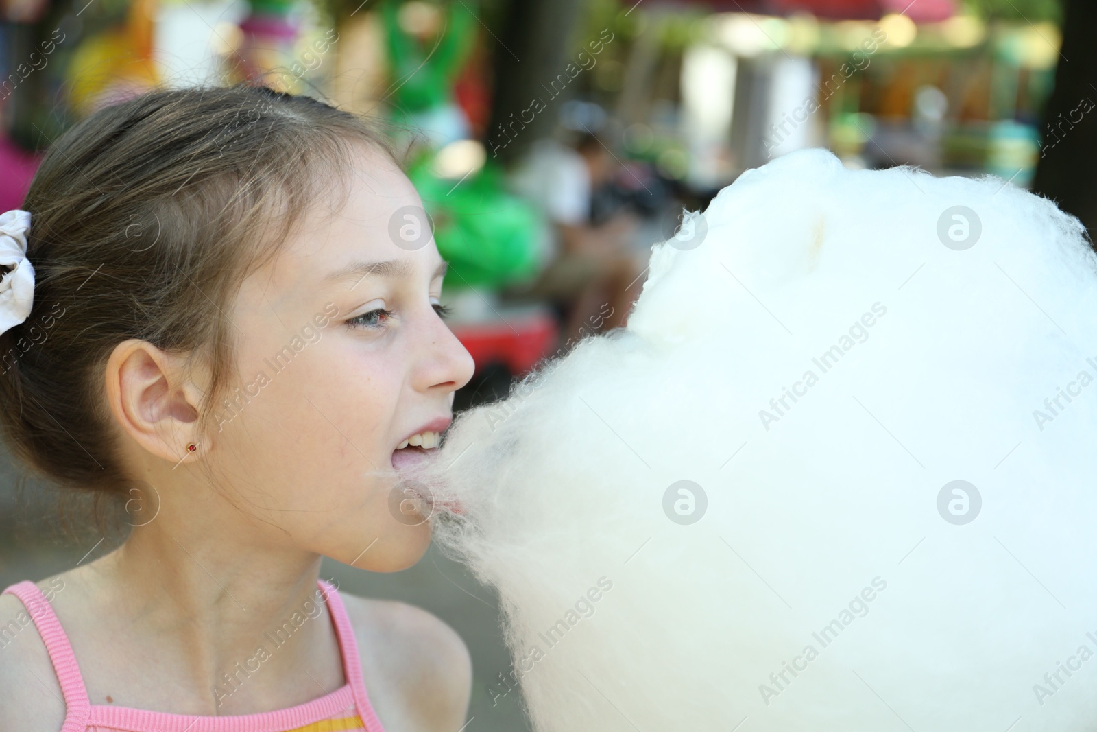 Photo of Portrait of little girl eating sweet cotton candy in park