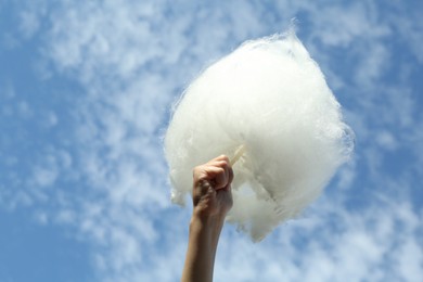 Photo of Little girl with sweet cotton candy against blue sky in park, low angle view