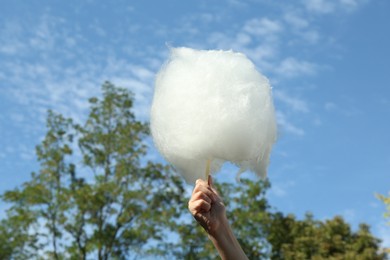 Photo of Little girl with sweet cotton candy against blue sky in park