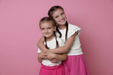 Photo of Portrait of cute little sisters on pink background