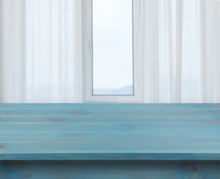 Image of Empty light blue wooden table near window with curtains. Space for design