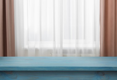 Image of Empty light blue wooden table near window with curtains. Space for design