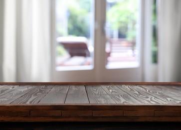 Image of Empty wooden table near window with curtains. Space for design