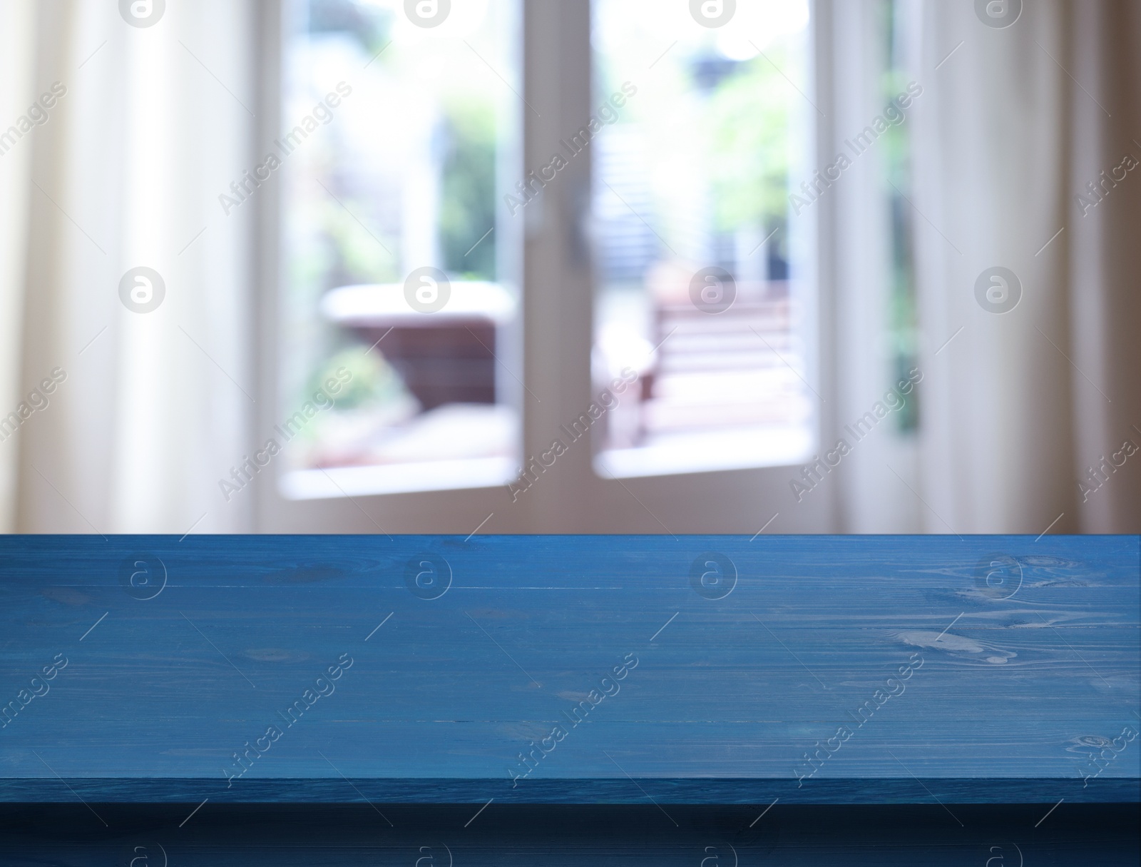 Image of Empty blue wooden table near window with curtains. Space for design