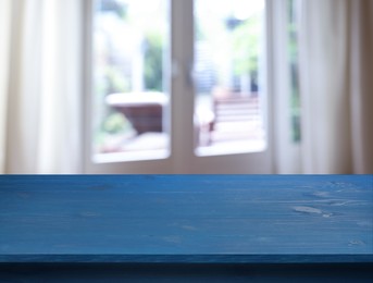 Image of Empty blue wooden table near window with curtains. Space for design