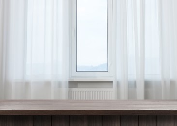 Image of Empty wooden table near window with curtains. Space for design