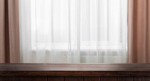 Image of Empty wooden table near window with curtains. Space for design