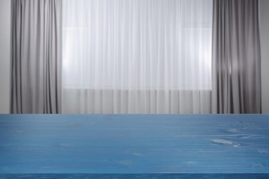 Image of Empty blue wooden table near window with curtains. Space for design