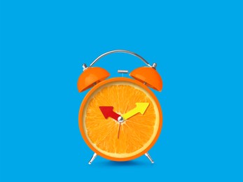 Juicy orange on alarm clock dial against light blue background. Creative poster