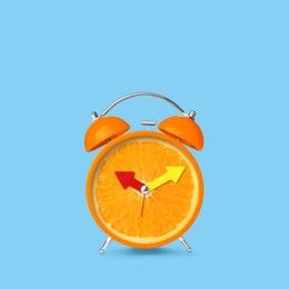 Image of Juicy orange on alarm clock dial against light blue background. Creative poster