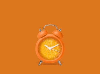 Image of Juicy orange on alarm clock dial against dark orange background. Creative poster