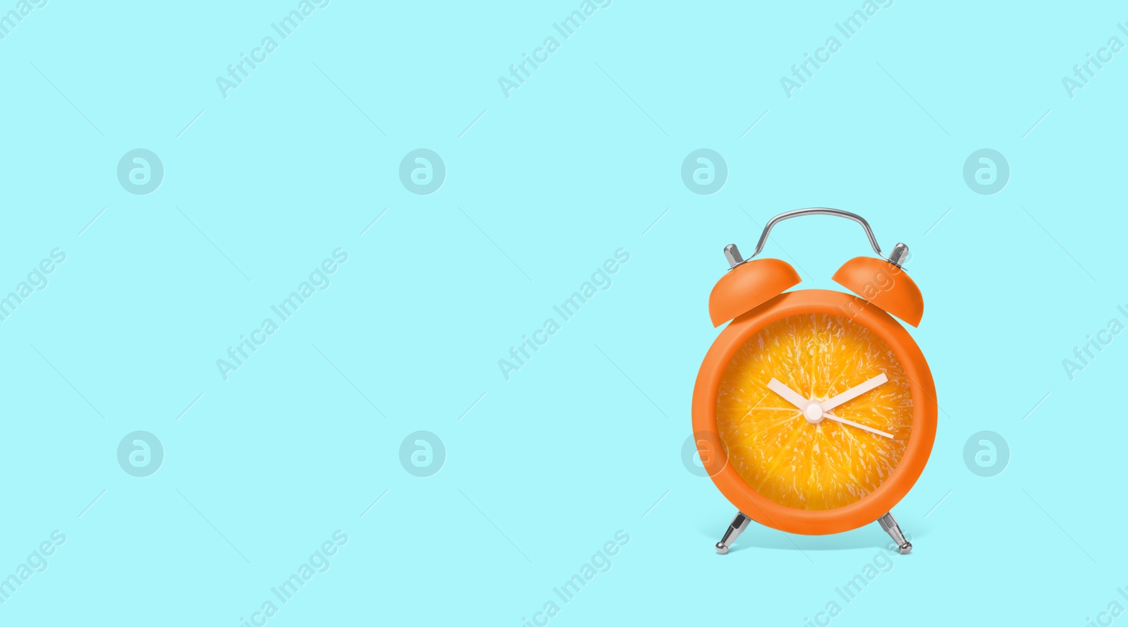 Image of Juicy orange on alarm clock dial against light blue background. Creative poster with space for text, banner design