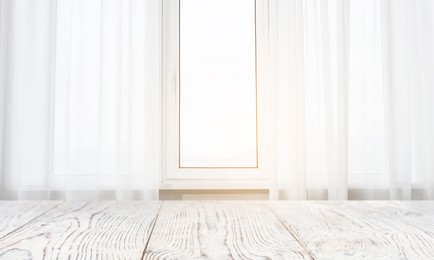 Image of Empty white wooden table near window with curtains. Space for design